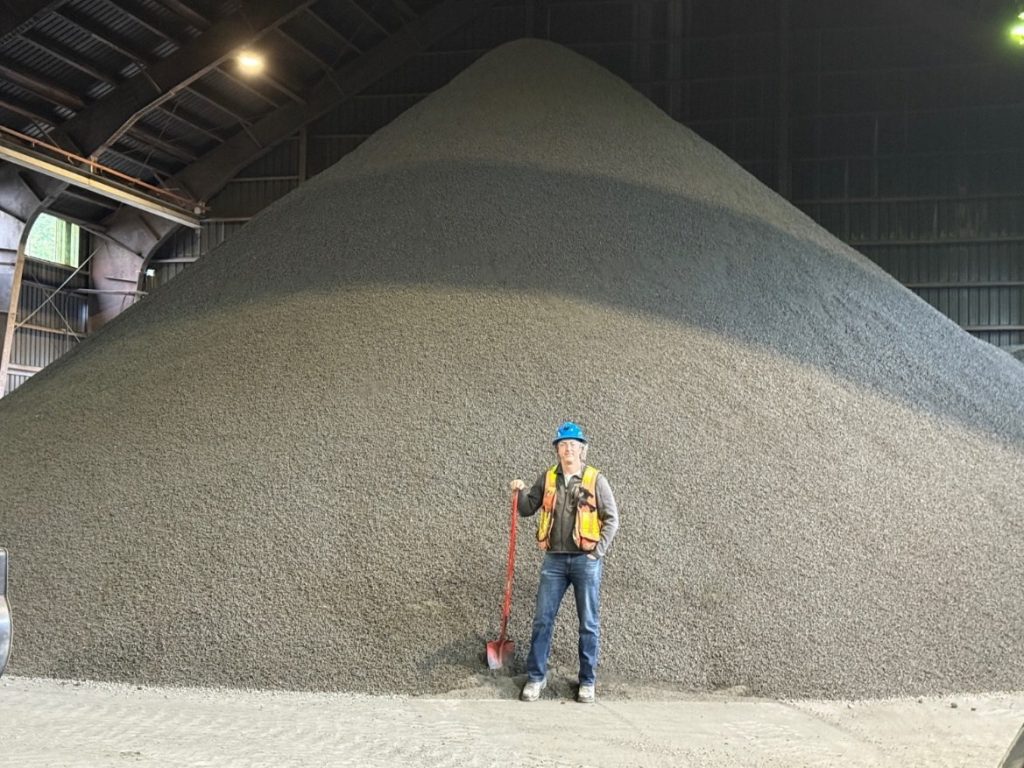 Photo of Bulk Sample at Stewart Bulk Terminal awaiting transport. Product has been crushed to ½" minus. Scottie COO Sean Masse for scale.